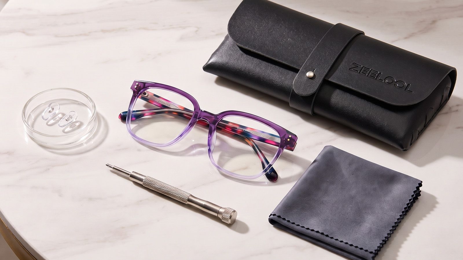 Glasses alongside nose pads, screwdriver, microfiber cloth, and case