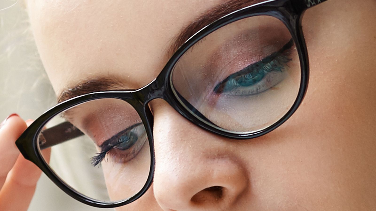 Close-up view of a woman wearing high-quality clear plano lenses in stylish cat-eye frames.